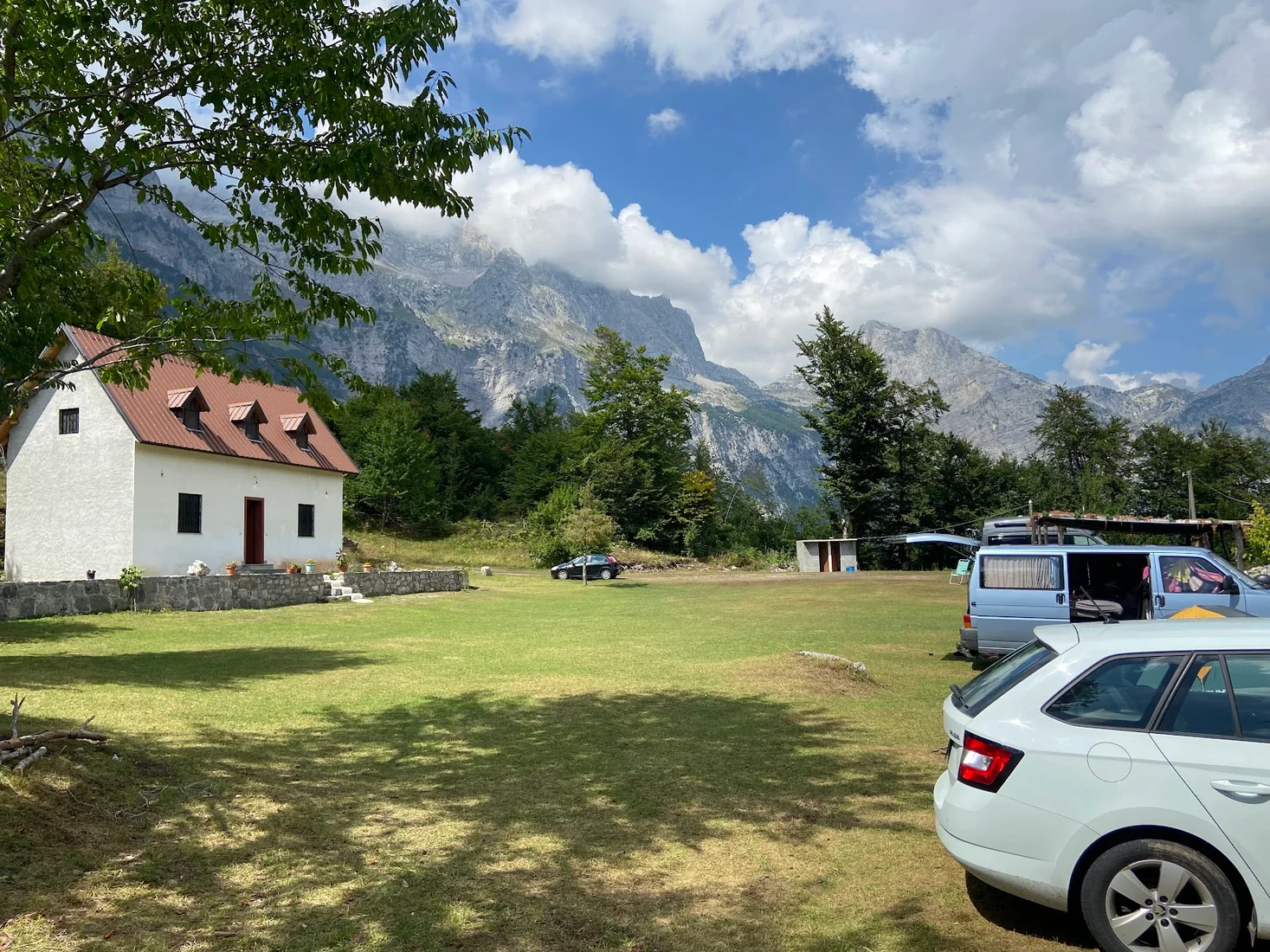 Grassy camping meadow with tents and campervans below the peaks at Camping Freskia in Theth
