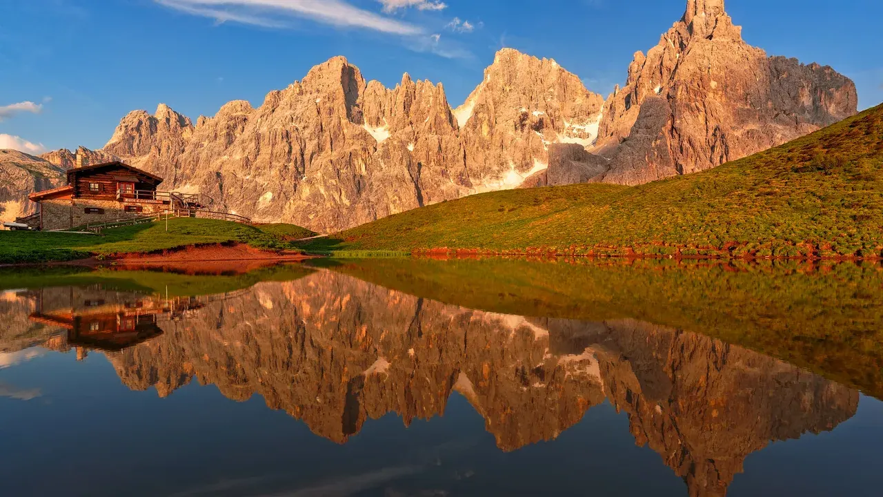 The jagged Pale di San Martino peaks of the Dolomites mirrored in an alpine lake at golden hour