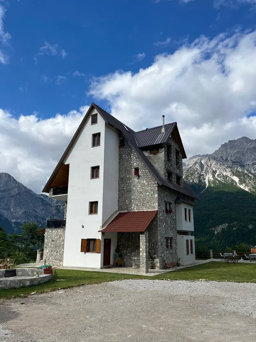 Tall stone-and-plaster guesthouse with a lawn terrace below the peaks at Valter & Drita's Guesthouse in Theth