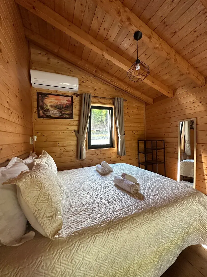 Bright wood-panelled chalet bedroom with a mountain-view window at Villa Ujevara e Vogël in Theth