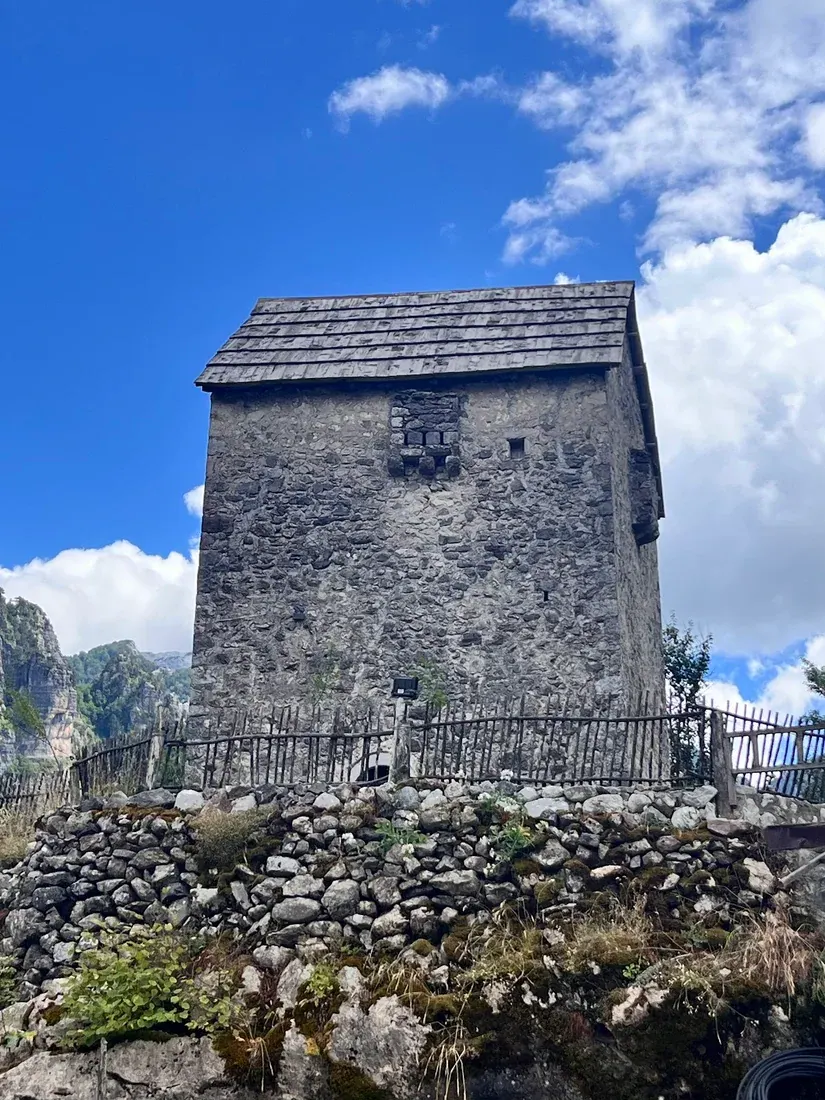 Close view of the Theth Lock-in Tower with its wooden shingle roof and dry-stone base