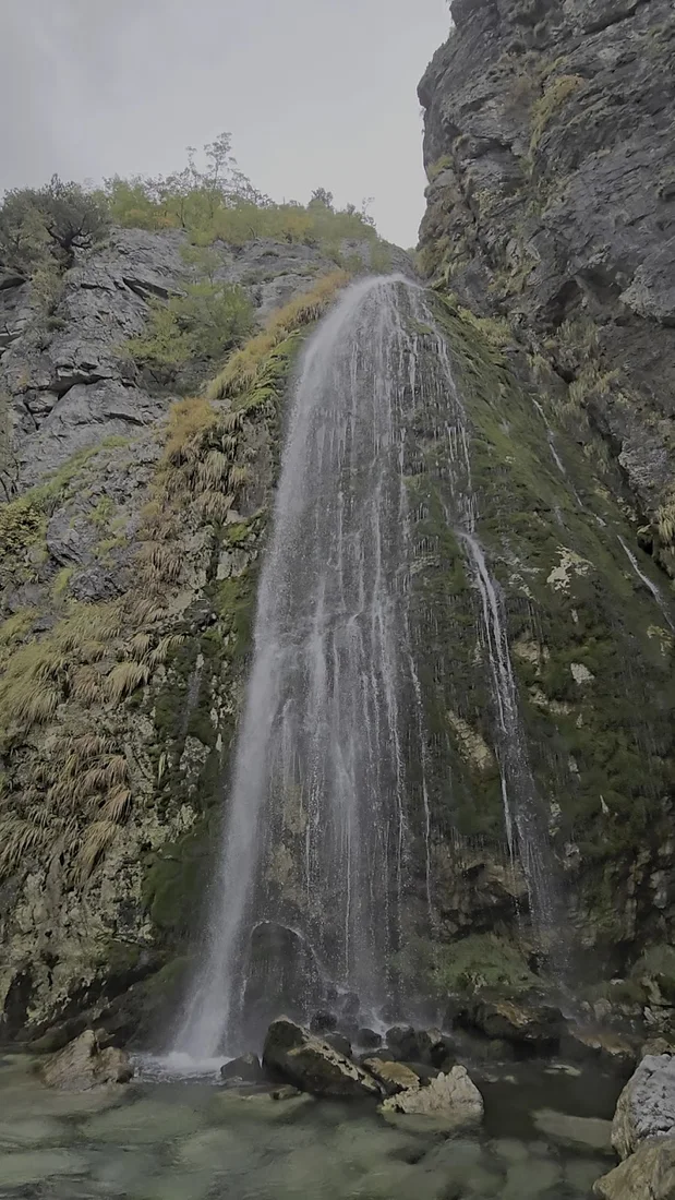 Grunas Waterfall dropping down a rock face near Theth village