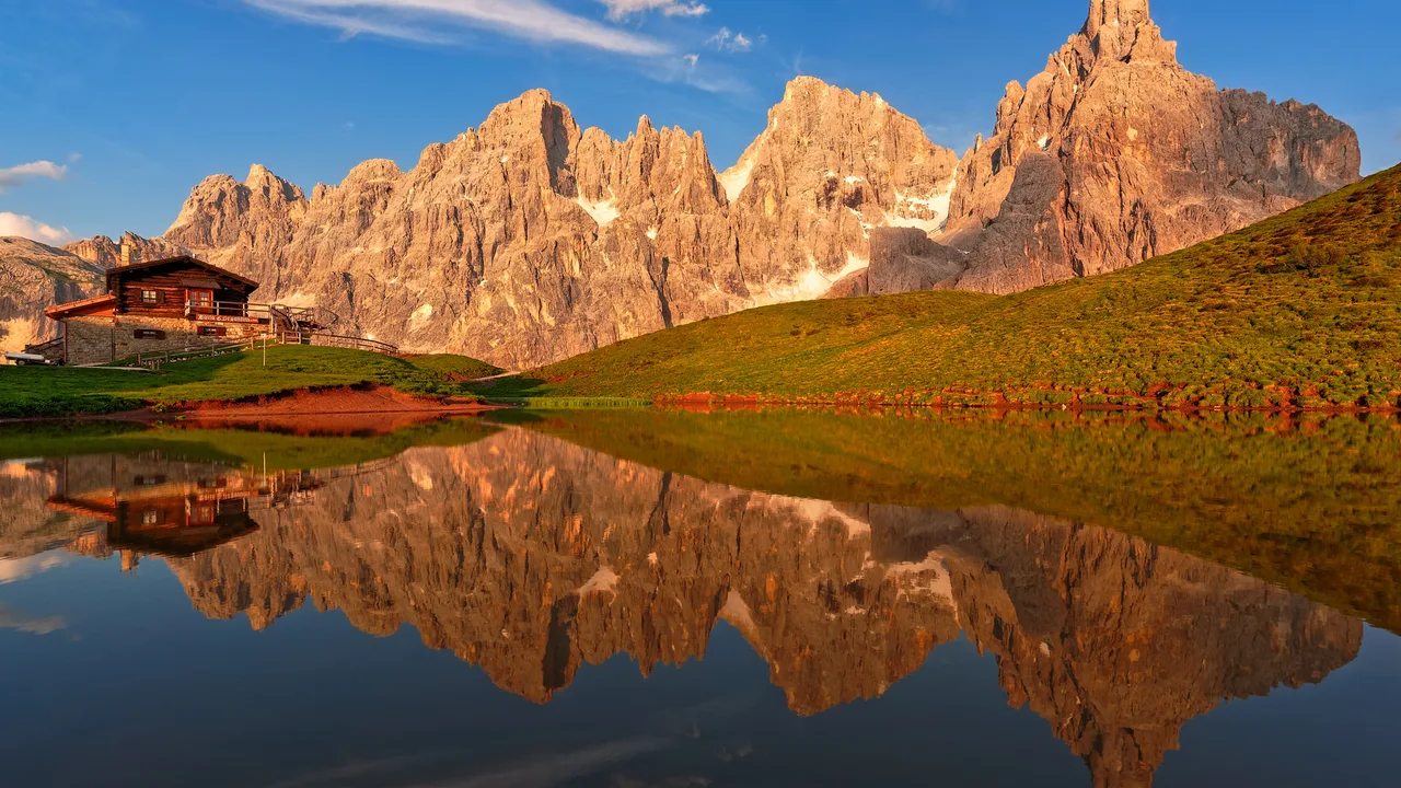 The jagged Pale di San Martino peaks of the Dolomites mirrored in an alpine lake at golden hour