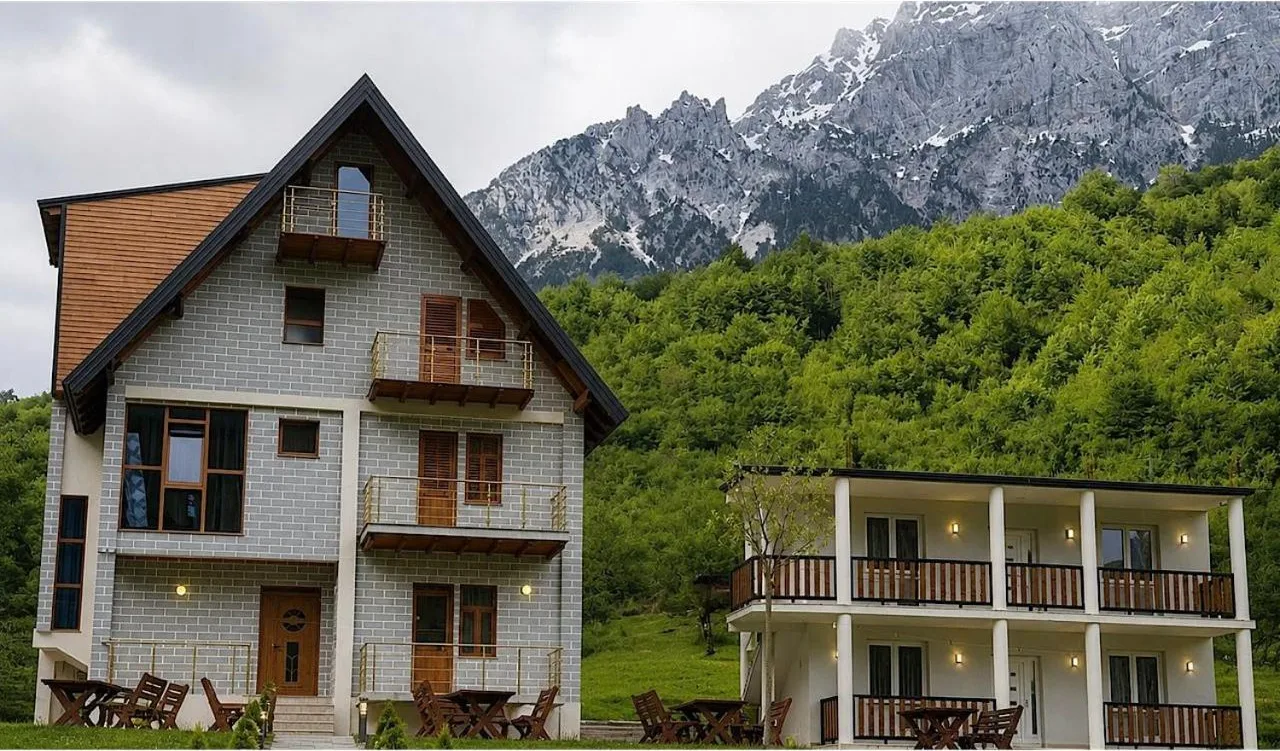 Grey-clad house with timber balconies below the snow-streaked peaks at Bujtina Malsori in Theth