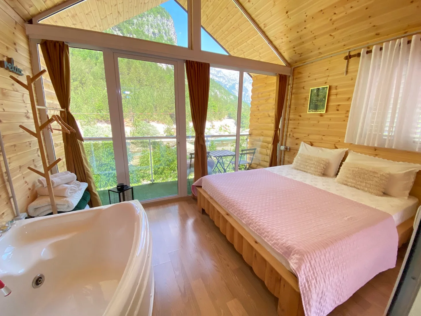 Timber-lined guest room with a corner bathtub and mountain-view window at Guesthouse Marashi in Theth