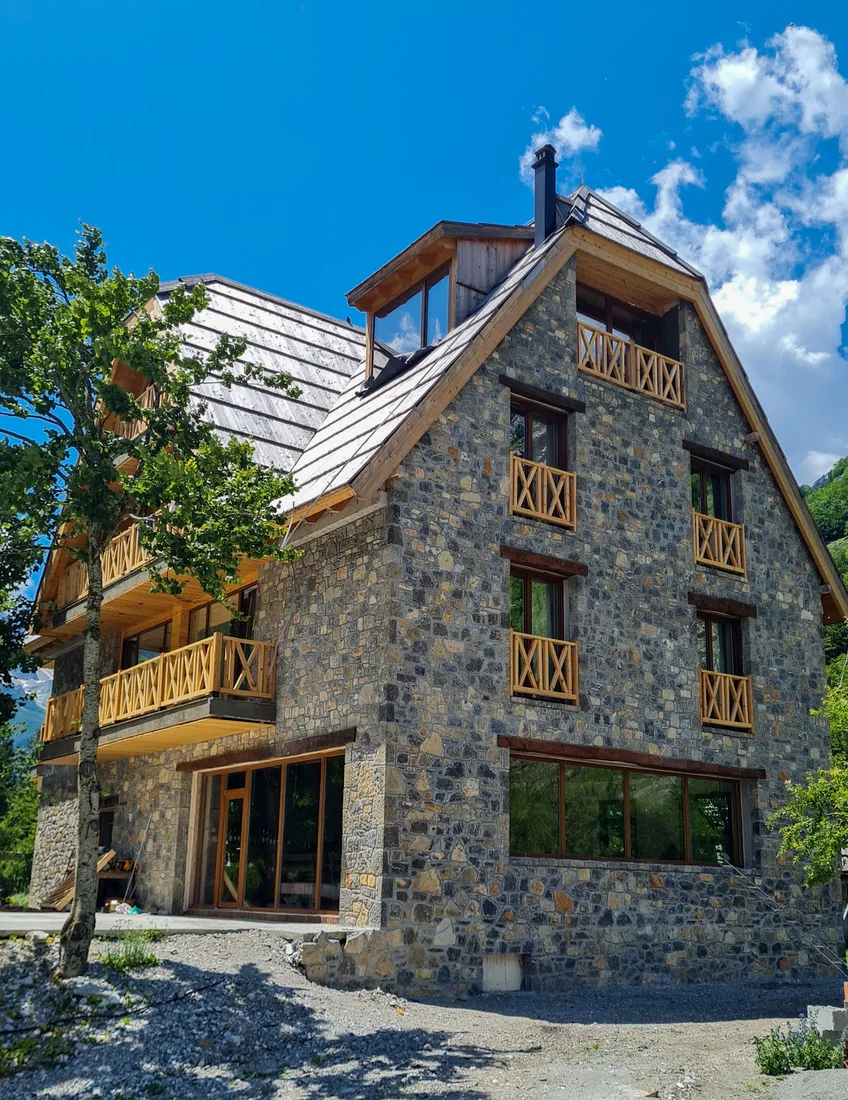 Tall stone kulla-style building with timber balconies at NeoKulla Hotel – Hikers Hive in Valbona