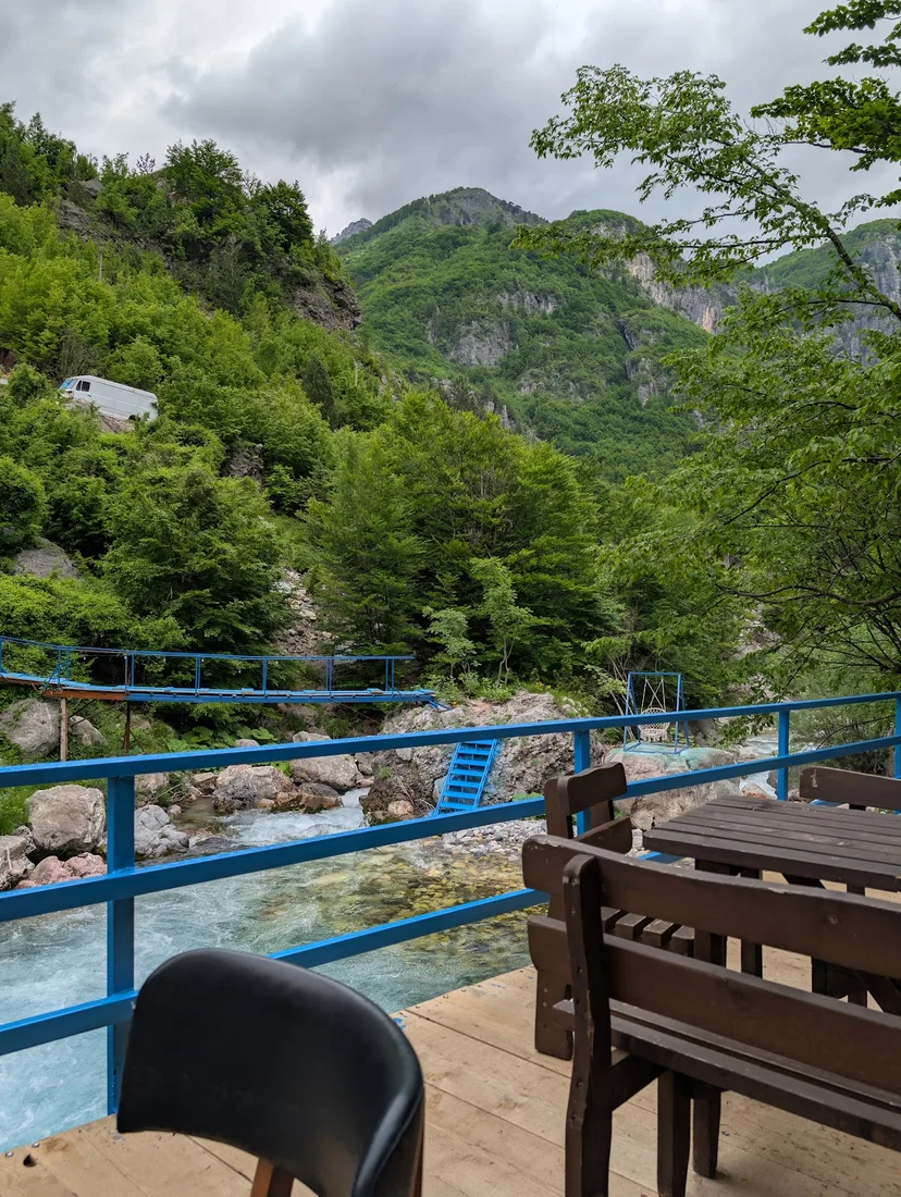 Blue-railed riverside terrace over the clear mountain stream at Blue River Bar & Grill in Theth