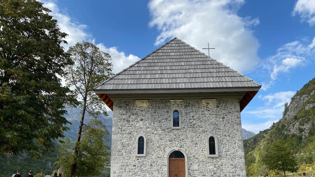 The stone church of Theth beneath the sheer limestone peaks of the Albanian Alps