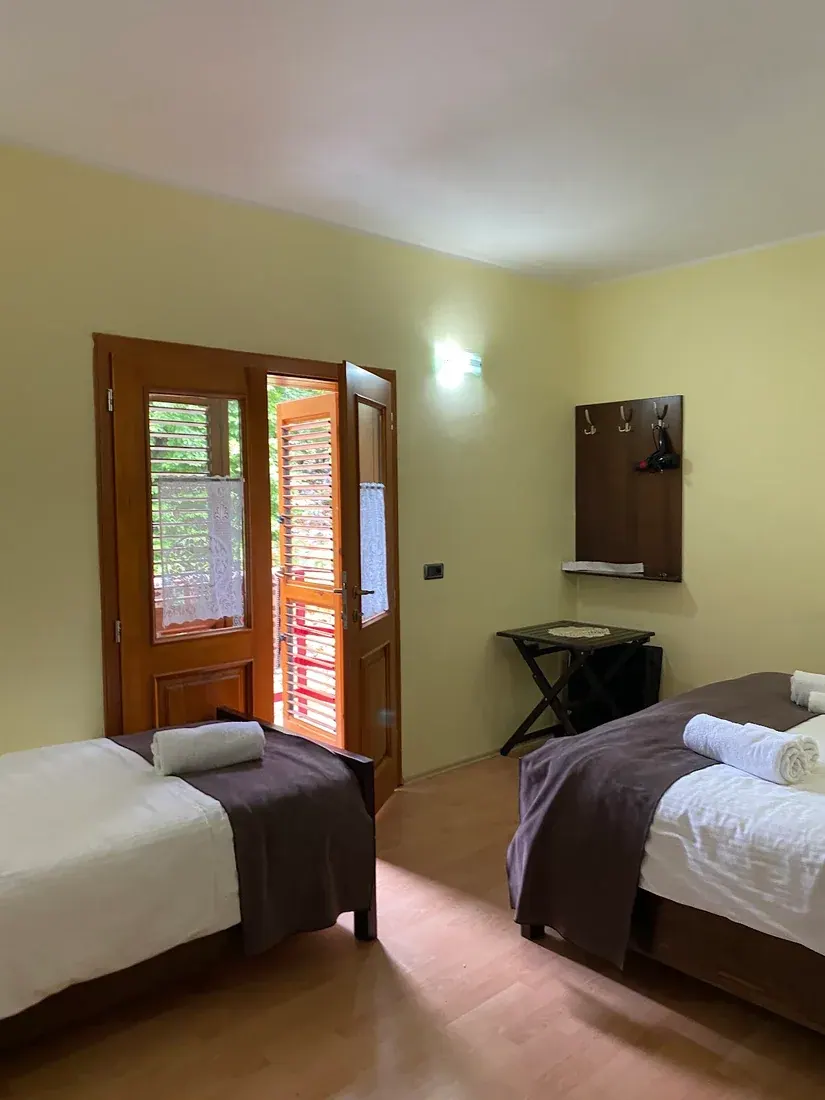 Bright twin guest room with shuttered balcony doors at Villa Dini in Dragobi, Valbona Valley
