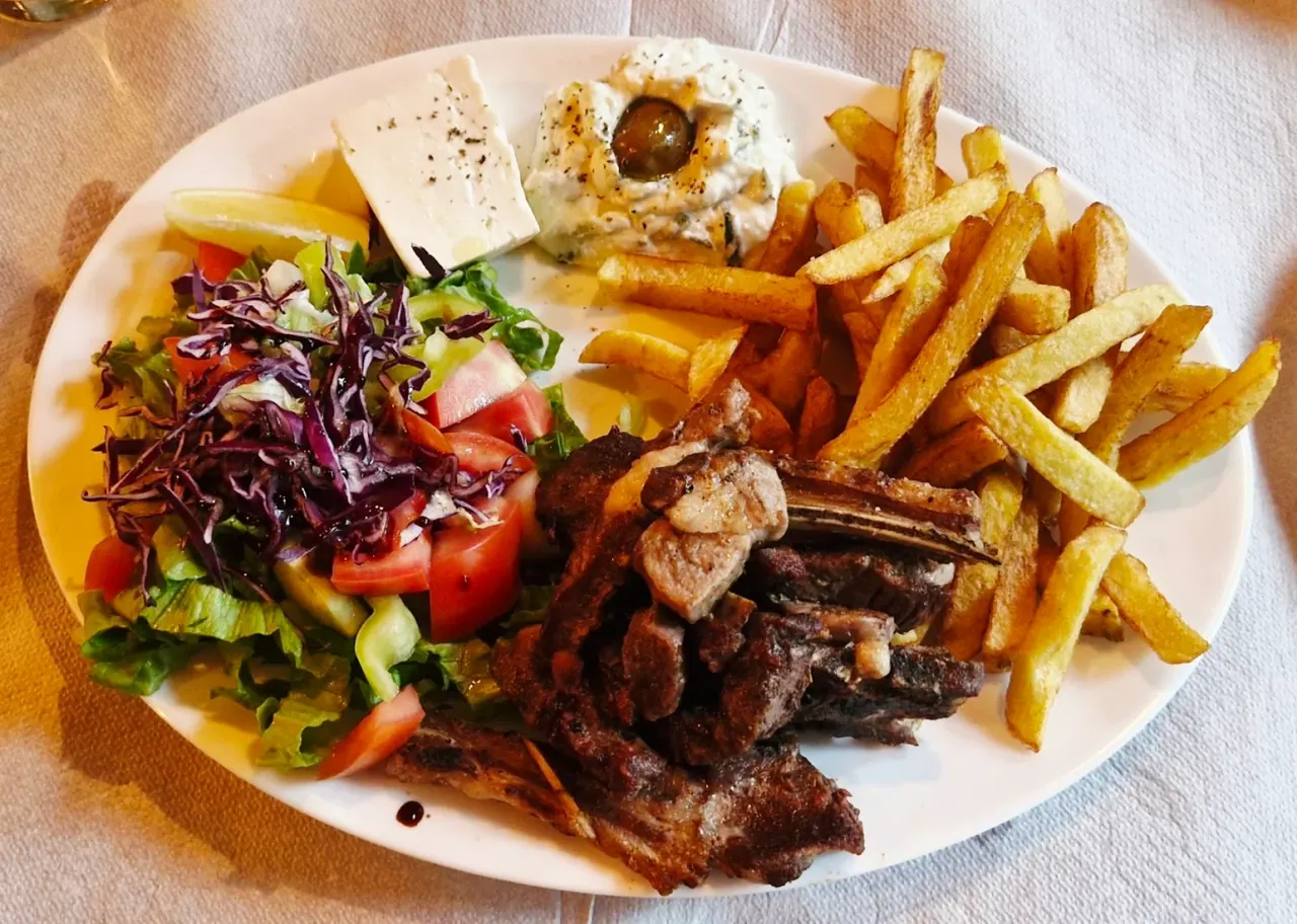Plate of grilled lamb chops with salad, feta and chips at Restaurant Tradita in Valbonë